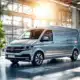 Сучасний службовий автомобіль в освітленому сонцем салоні Van den Hurk Bedrijfswagens, оточений фінансовими символами та контрактними документами.