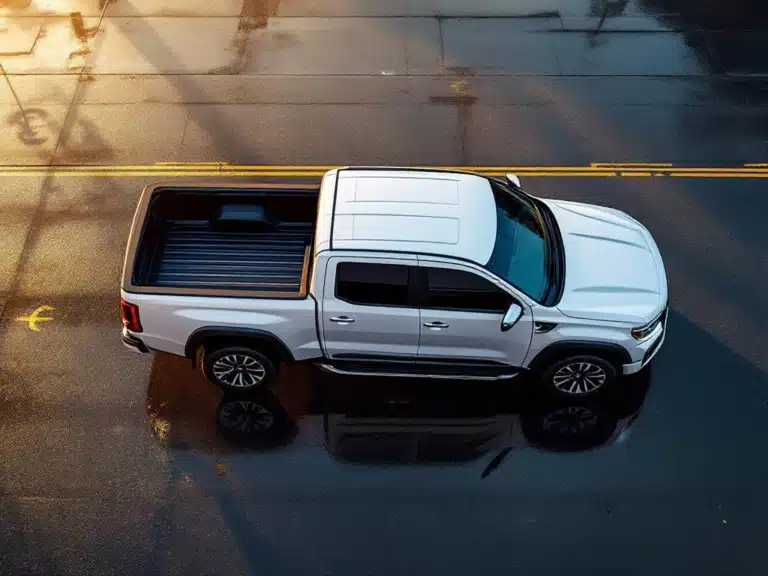 Witte moderne dubbele cabine pickup truck van bovenaf gefotografeerd op nat asfalt met gouden uur verlichting
