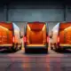 Trois fourgons commerciaux électriques modernes avec portes arrière ouvertes présentent des zones de chargement spacieuses sur un sol industriel en béton.
