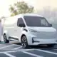 White electric van with charging gate and LED headlights at charging station on tarmac