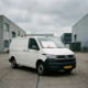 Autobuz alb al companiei de electricitate, aflat într-o zonă industrială, cu un document oficial cu ștampilă roșie pe capota motorului.